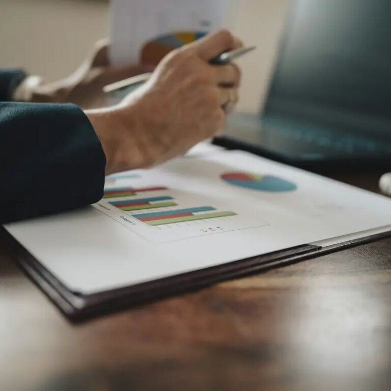 Female hands holding paperwork with statistical financial report on it with graphs and charts