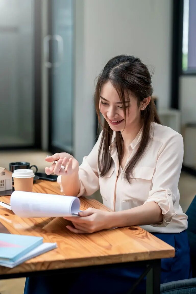 Happy young Asian businesswoman to work holding documents at the office.