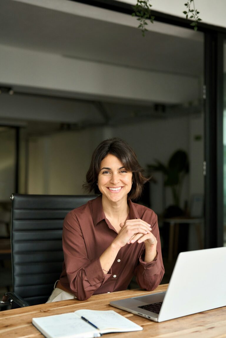 Vertical portrait of confident businesswoman leader in her 30s at work desk.