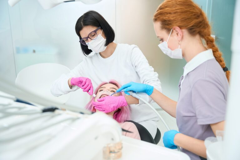 Woman dentist performs a dental procedure to a young patient